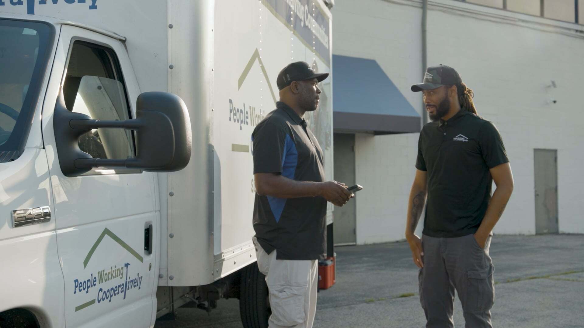 Two PWC employees talking beside a box truck