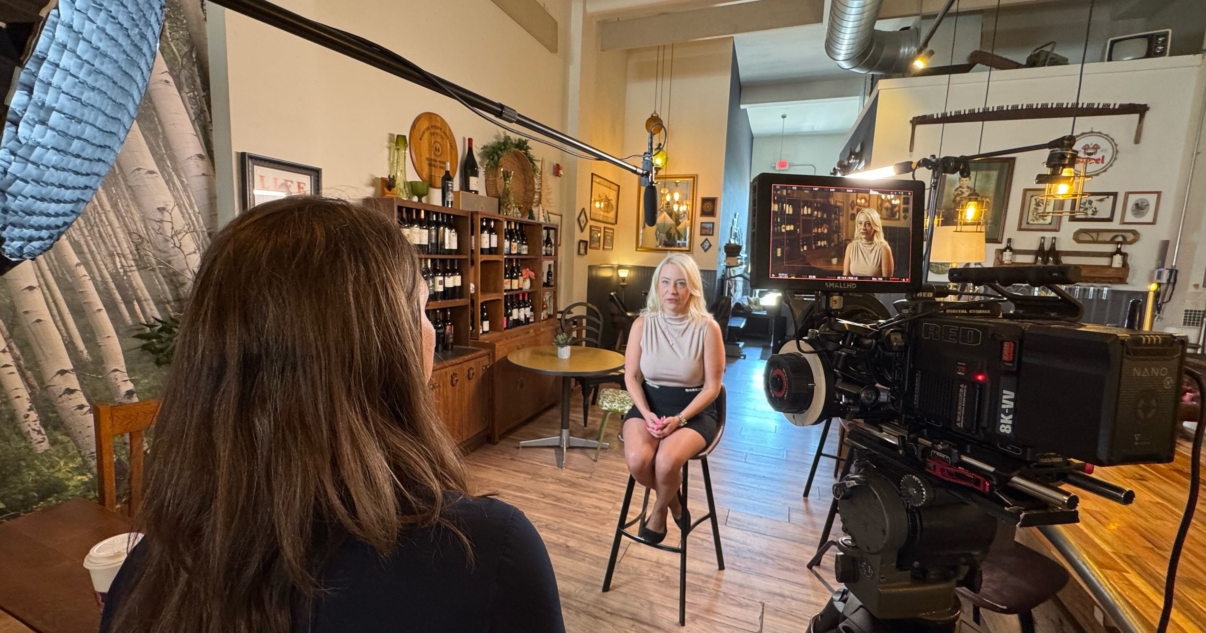 Behind-the-scenes photo of a woman being interviewed on camera at a bar. 